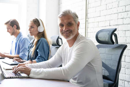 Man Working At Desk In Busy Creative Office.