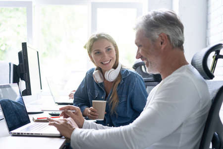 Team Working At Desks In Busy Office.