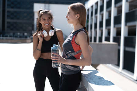 Two female friends relax after running in city.の写真素材