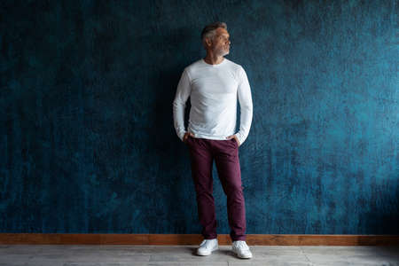 Casual Grey-haired Mature handsome man portrait over dark blue wall background.の写真素材