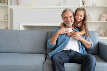 Happy sweet girl hugging her father at home.の写真素材