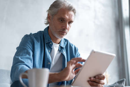 Handsome businessman working on tablet from home.