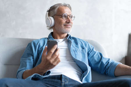 Man at home on sofa listening a music with a smartphone.