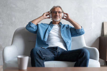 Man at home on sofa listening a music with a smartphone.の写真素材