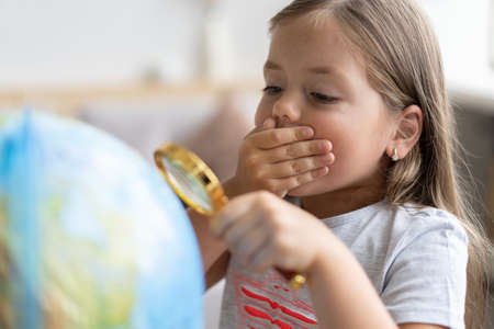 education and school concept. child girl pointing at globe.