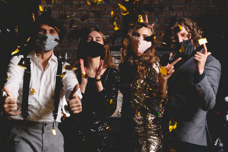 Corona virus pandemic. Group of beautiful young people in protective medical mask dancing, looking happyの写真素材