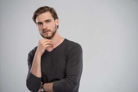 Portrait of a smart young man standing against grey background.の写真素材