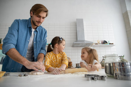 smiling father and daughters baking in the kitchen and having fun