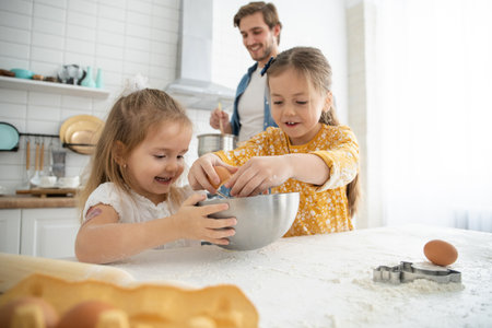 smiling father and daughters baking in the kitchen and having funの写真素材