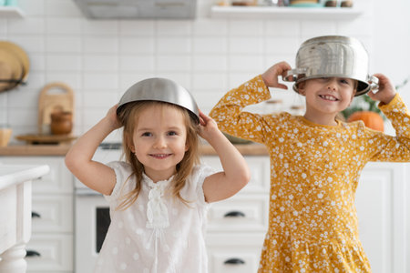 Cute little kids wearing bowl as helmet and playing at home.の写真素材