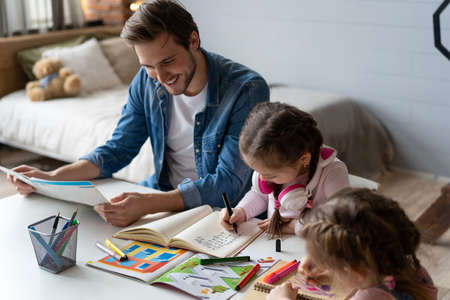 A father helping his little daughter to do her homework for the school