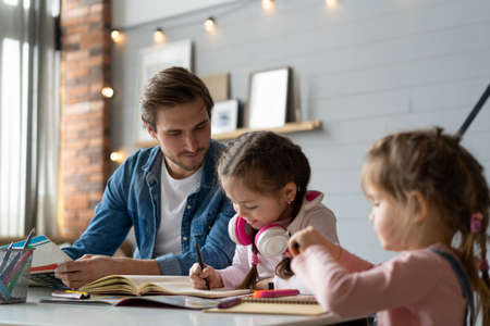 A father helping his little daughter to do her homework for the school