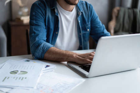 Entrepreneur working with a laptop and holding a document in a little office or home