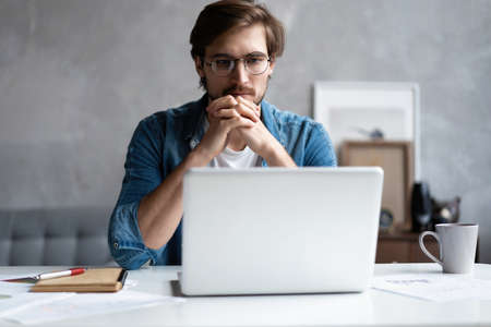 Thoughtful man looking away while sitting at his working place in office