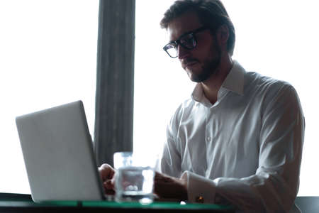 Young successful businessman working on a laptop while sitting in cafeの写真素材