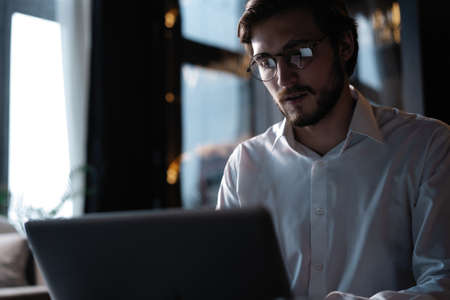 Young successful businessman working on a laptop while sitting in cafeの写真素材