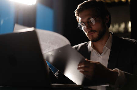 Male businessman works with business reports and financial charts. Paperwork late at nightの写真素材