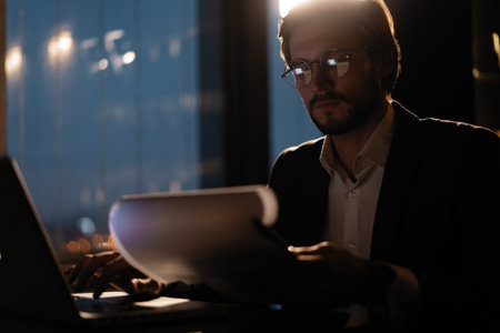 Male businessman works with business reports and financial charts. Paperwork late at night