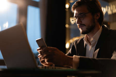 Handsome young businessman working on a laptop at his office desk late into the night.