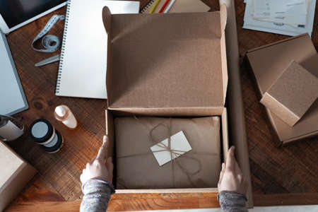 Top view of female business owner working, packing the order for shipping to customer