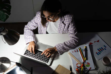 Confident Young Indian Mixed-race Businesswoman Working in Office at Night. Girl Working Overtime