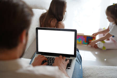 Male remote working from home and having work confrence video call while daughters playing on the floor.の写真素材