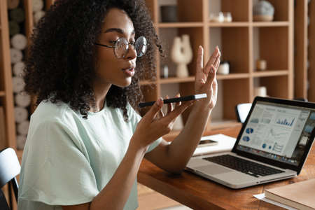 Young african american woman dictating voice message to client, chatting with friend, recording...
