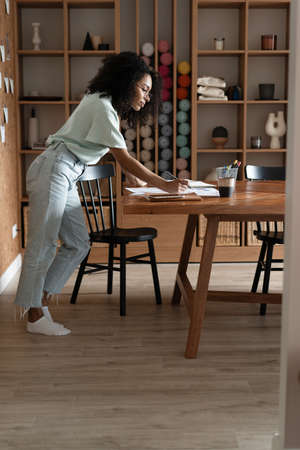 Mixed-race beautiful businesswoman working with papers while standing in modern officeの写真素材