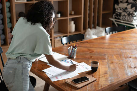 Mixed-race beautiful businesswoman working with papers while standing in modern office