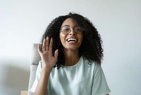 Head shot portrait friendly talking mixed race woman, looking at camera, making video call, recording vlog or webinarの写真素材