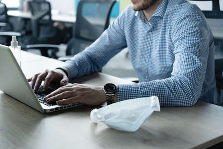 Handsome office worker working in office and taking his medical protective mask off.の写真素材