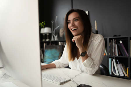 Attractive young woman working at office, using contemporary desktop computer.の写真素材