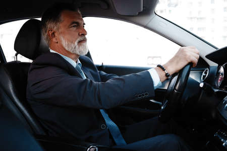 Mature successful businessman riding in the car.の写真素材