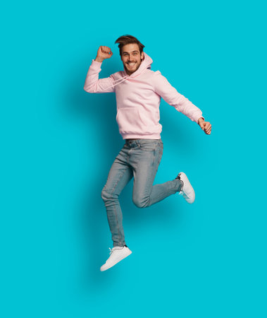 Full size photo of young happy excited smiling positive man jumping isolated on light blue color...