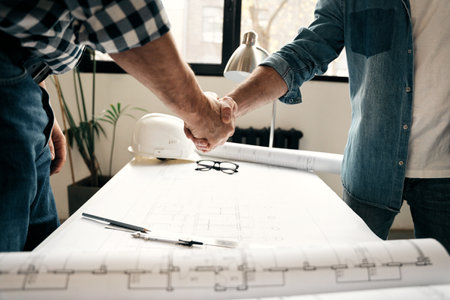 Architect and engineer workers shaking hands while working for teamwork and cooperation concept...