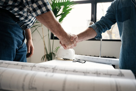 Architect and engineer workers shaking hands while working for teamwork and cooperation concept...