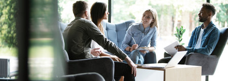 Group of young modern people in smart casual wear discussing business while working in the creative officeの写真素材