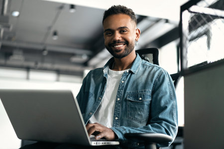 Portrait of Stylish Businessman Works on Laptop, Does Data Analysis and Creative Designer Looks at Camera and Smilesの写真素材