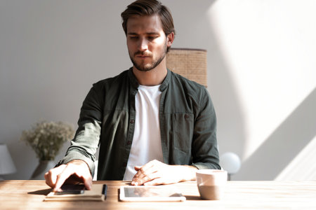 Young employee at workplace using mobile phone, checking social media on smartphone, taking break,...