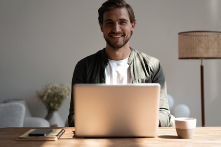 Male remote working from home and having work conference video call. Freelancer working on laptop at home officeの写真素材