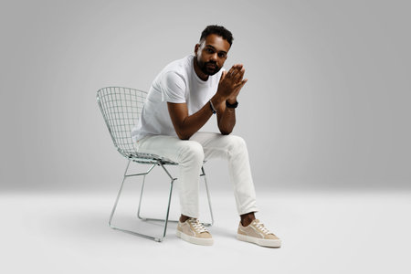 Handsome young african american guy sitting on stool, posing in studio - isolated.の写真素材