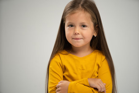 Adorable six years old girl isolated on white studio background, pretty brown-haired fringe hairstyle european appearance child pose indoor smiling look at camera, generation Z conceptの写真素材