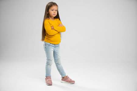 Full length of adorable six years old girl isolated on white studio background, pretty brown-haired fringe hairstyle european appearance child pose indoor smiling look at camera, generation Z conceptの写真素材