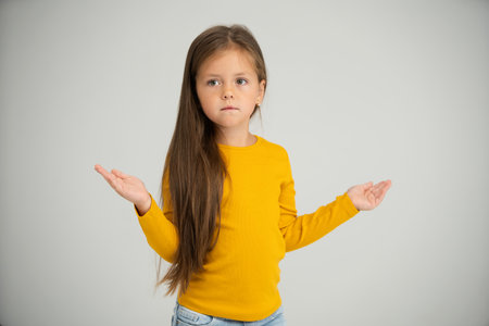 Adorable six years old girl isolated on white studio background, pretty brown-haired fringe hairstyle european appearance child pose indoor smiling look at camera, generation Z conceptの写真素材