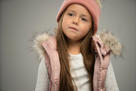 Portrait of little girl, child, posing in warm jacket and hat isolated over white background. Concept of childhood, fashion, emotions, lifestyle, beauty, facial expression. Copy space for adの写真素材