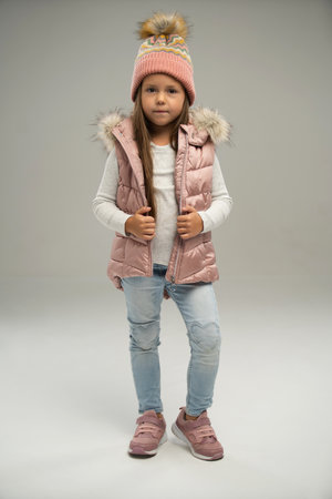 Full length of little girl, child, posing in warm jacket and hat isolated over white background. Concept of childhood, fashion, emotions, lifestyle, beauty, facial expression. Copy space for adの写真素材