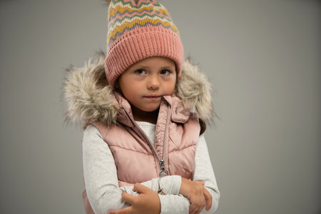 Portrait of little girl, child, posing in warm jacket and hat isolated over white background. Concept of childhood, fashion, emotions, lifestyle, beauty, facial expression. Copy space for adの写真素材