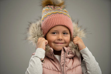 Portrait of little girl, child, posing in warm jacket and hat isolated over white background. Concept of childhood, fashion, emotions, lifestyle, beauty, facial expression. Copy space for adの写真素材