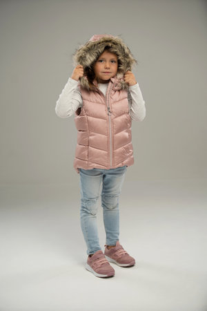 Full length of little girl, child, posing in warm jacket and hat isolated over white background. Concept of childhood, fashion, emotions, lifestyle, beauty, facial expression. Copy space for adの写真素材