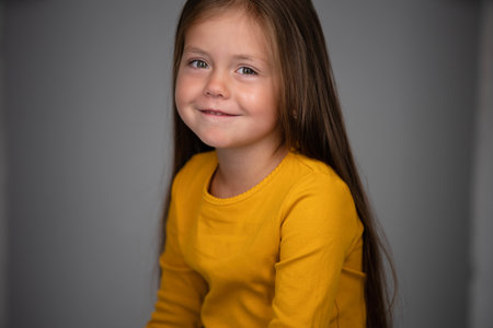 Adorable six years old girl isolated on white studio background, pretty brown-haired fringe hairstyle european appearance child pose indoor smiling look at camera, generation Z conceptの写真素材